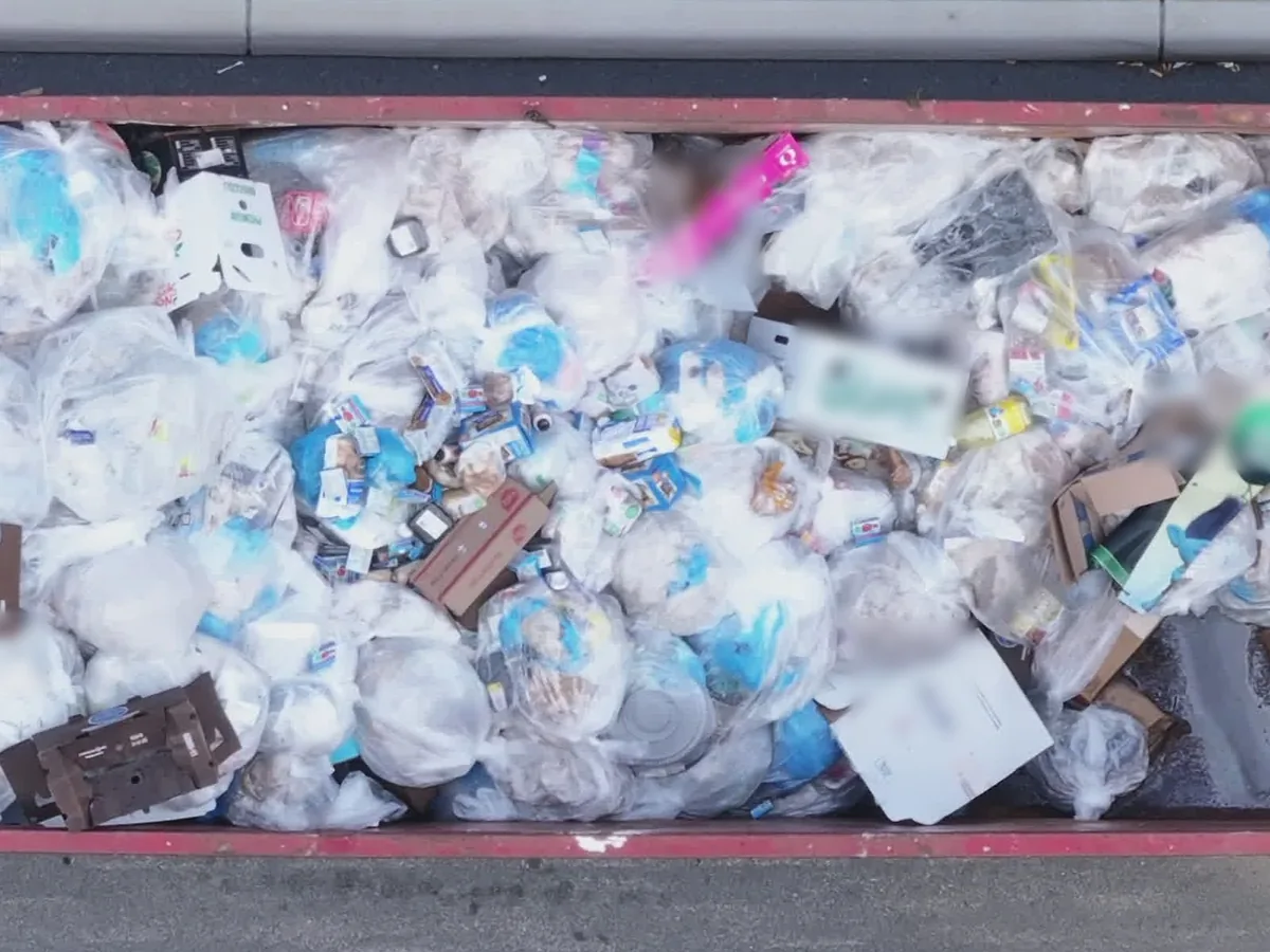 Top-down view of a roll-off dumpster filled with bagged household trash and boxes, 30 yard dumpster rental