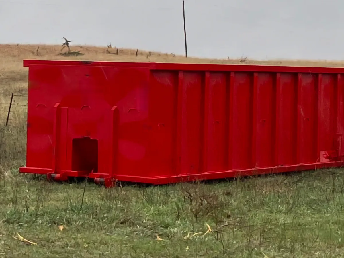 Red roll-off dumpster on a grassy lot, 30 yard dumpster rental
