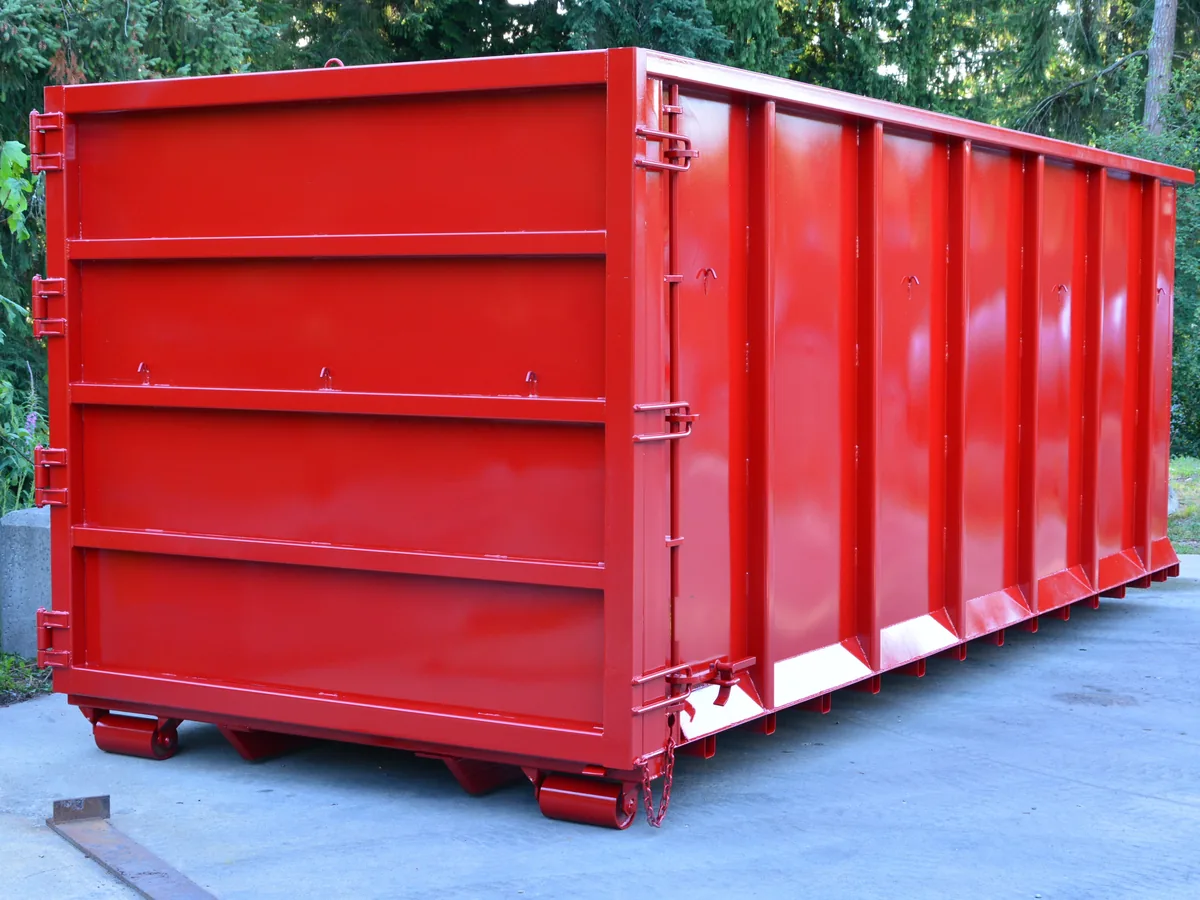 Tall red roll-off dumpster with high steel walls on a concrete pad, 40 yard dumpster rental