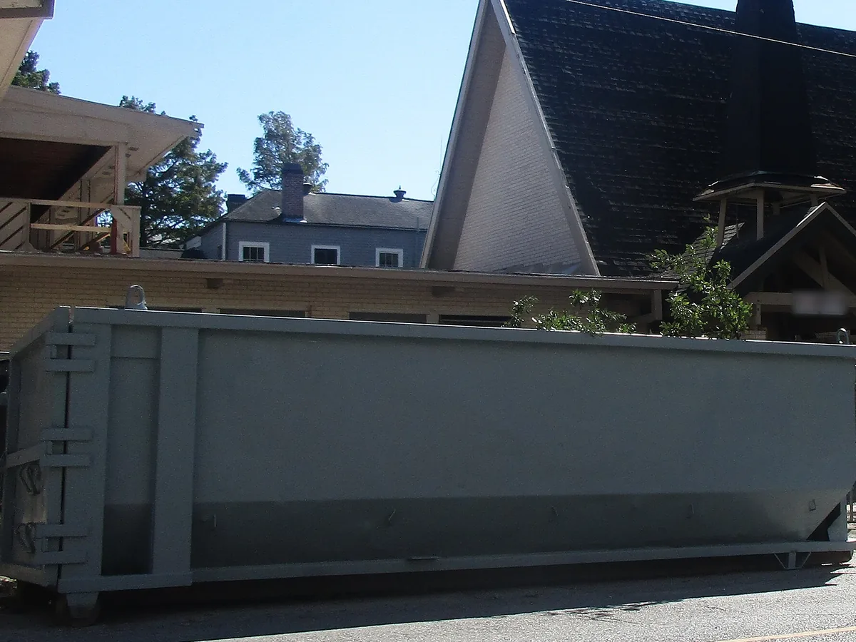 Gray roll-off dumpster outside a church under renovation, commercial dumpster rental