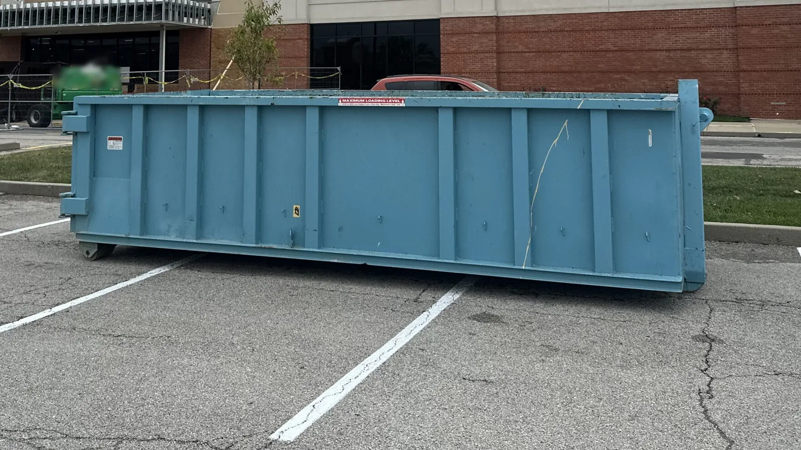 Blue roll-off dumpster in a retail parking lot in front of a store under renovation, commercial dumpster rental