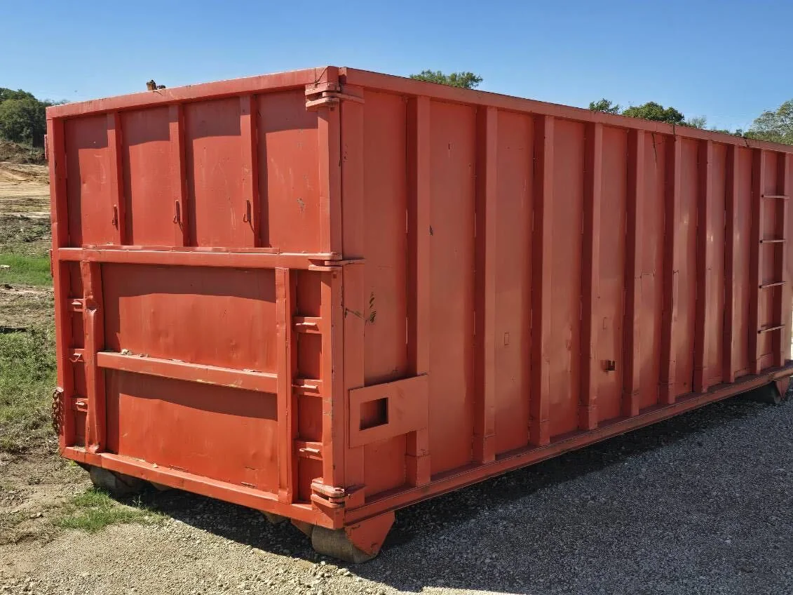 Red roll-off dumpster on a gravel lot, construction dumpster rental
