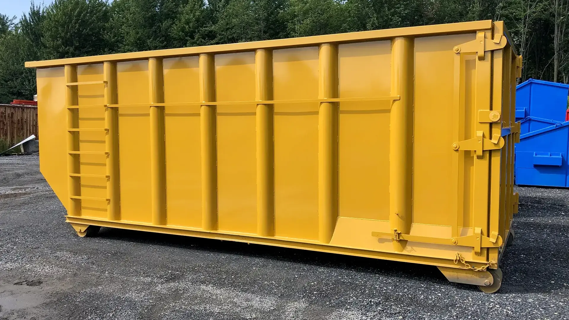 Tall yellow roll-off dumpster with a side ladder on a gravel lot, dumpster rental